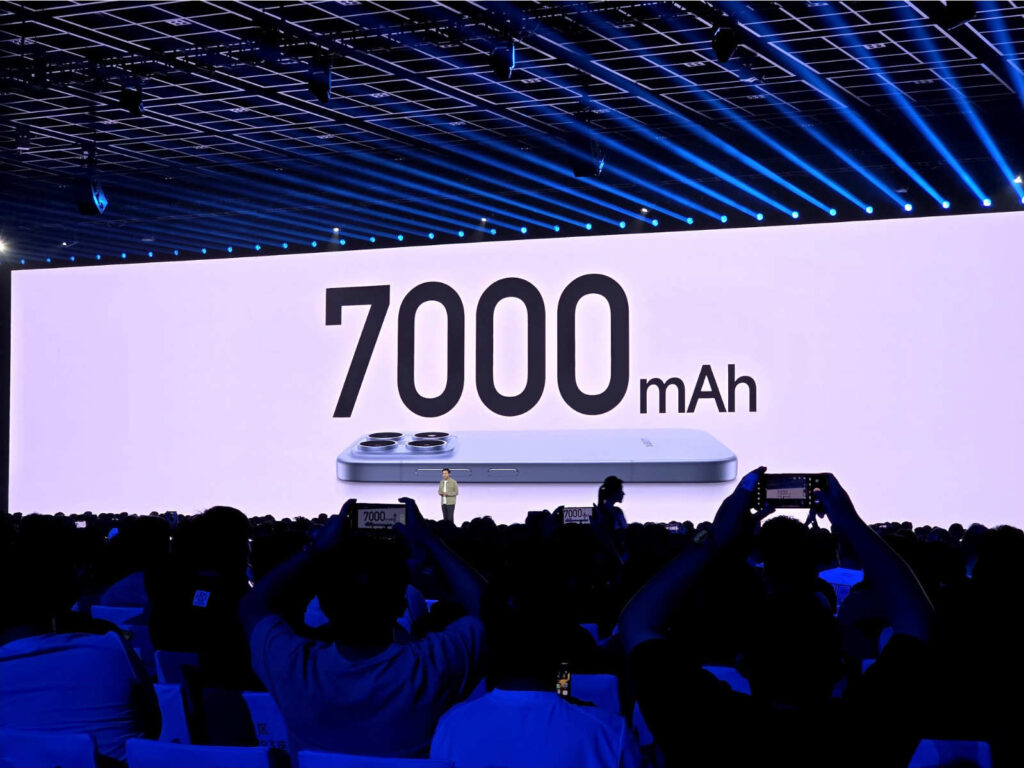 A picture from a crowded room with a projection of the Xiaomi 17 phone with 7,000 mAh written above it.